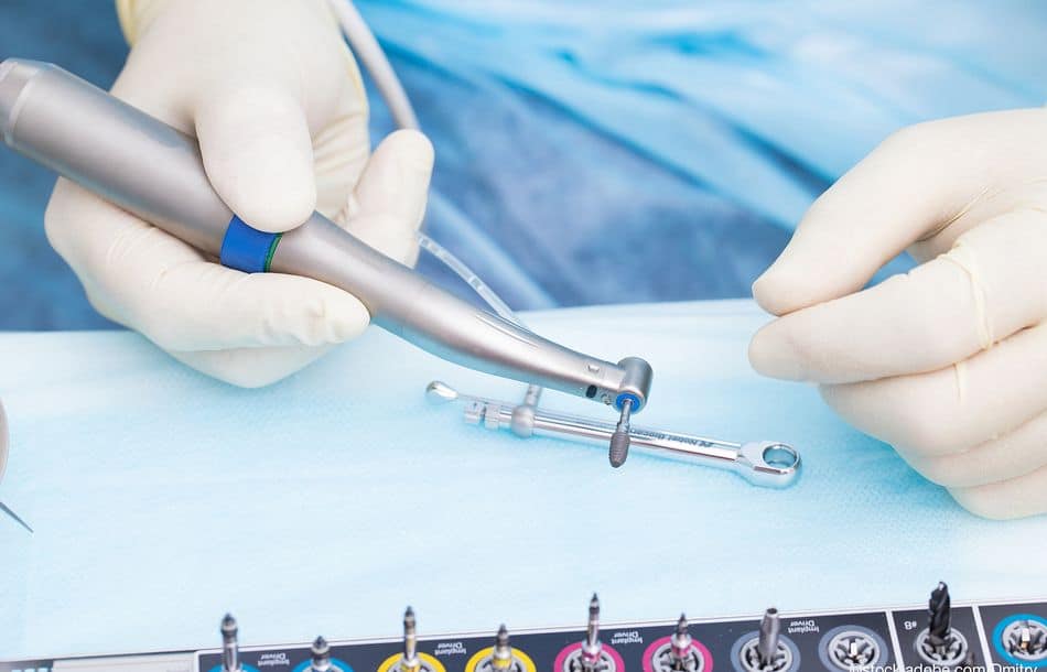 Close-up dental implant in the hands of a dentist. An implantati