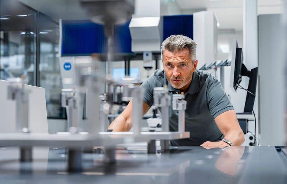 Engineer with gray hair examining machinery in factory